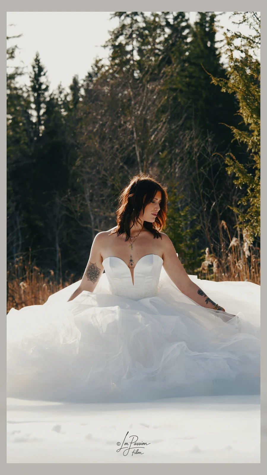 Mariée en robe blanche assise dans la neige