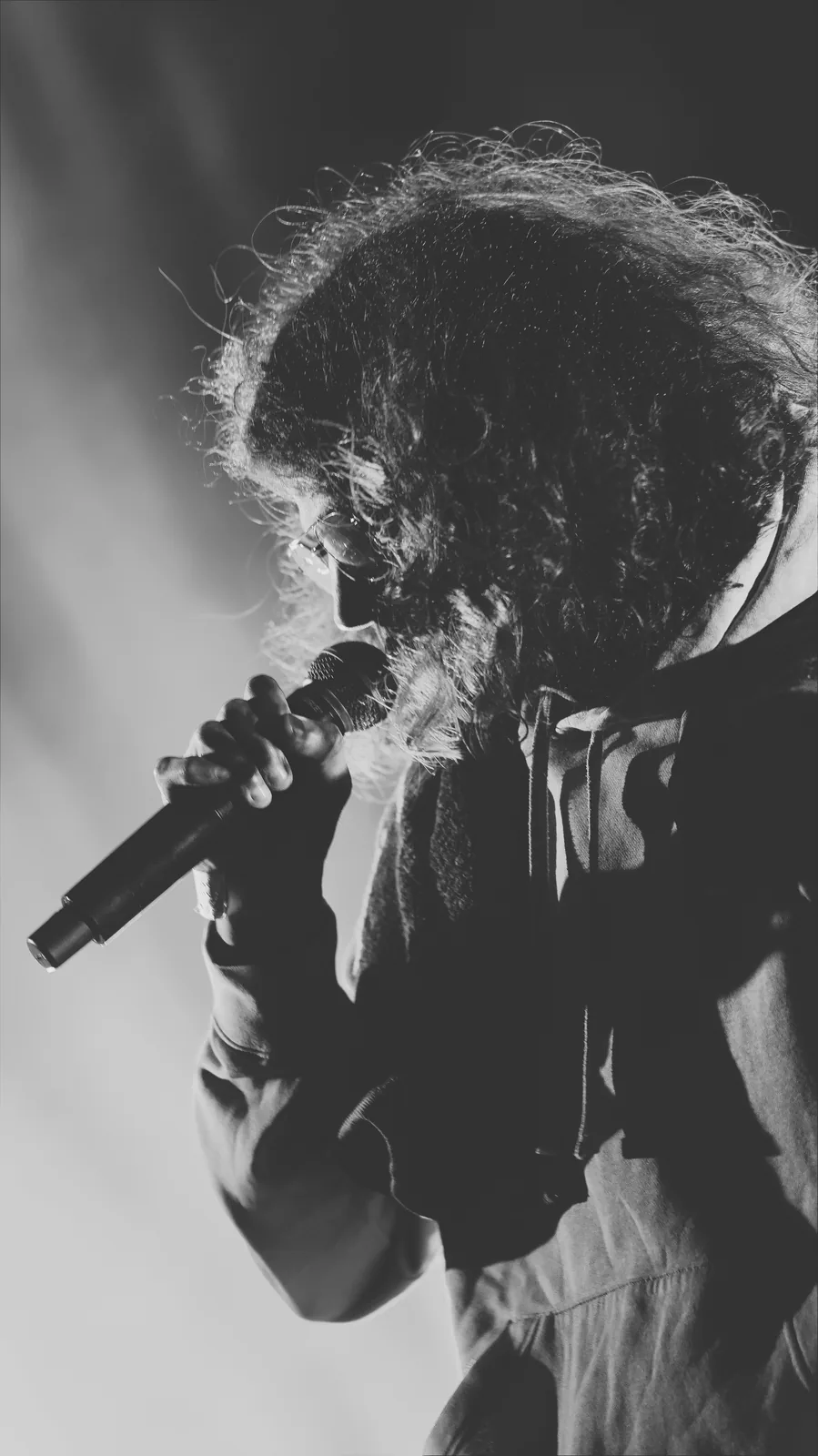 Chanteur penché sur son micro, noir et blanc
