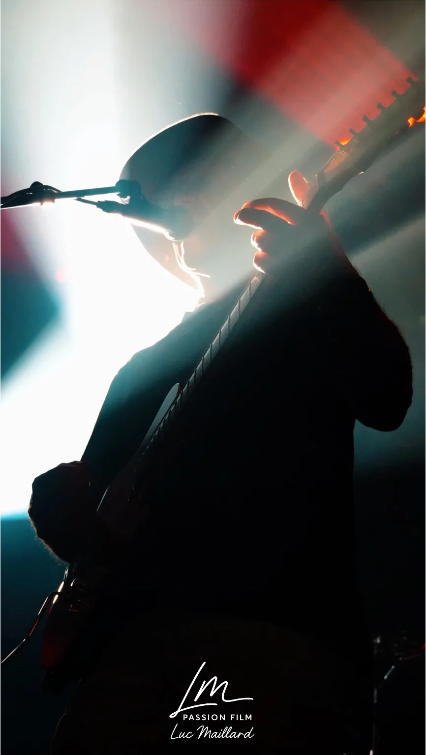 Guitariste en contre-jour, silhouette découpée par les projecteurs